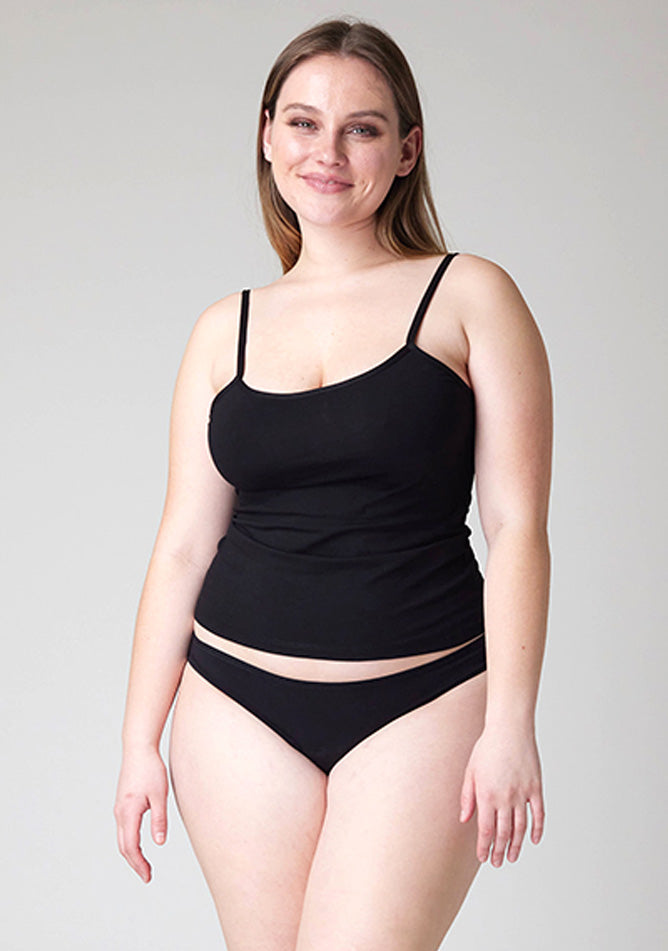 Close-up image of a five-foot-five, size 14 model wearing Ugly Pants' Black Bikini Brief Period Pants in light to moderate absorbency, paired with a black cami top.