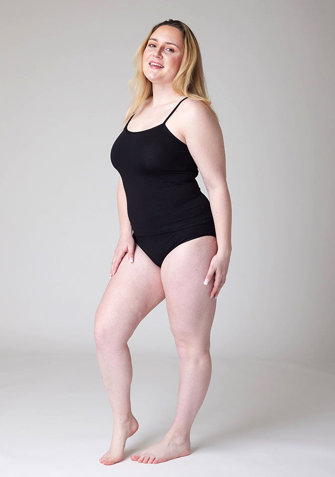 Quarter front image of a five foot three, size 12 model wearing Ugly Pants' Black Overnight flow sleep set with a black cami top.