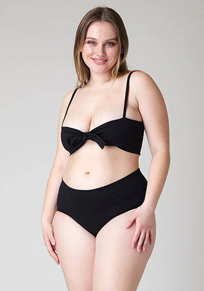 Close-up image of a five-foot-five, size 14 model wearing Ugly Pants' Black Overnight flow sleep set with matching black crop top, featuring a self tie detachable bow.