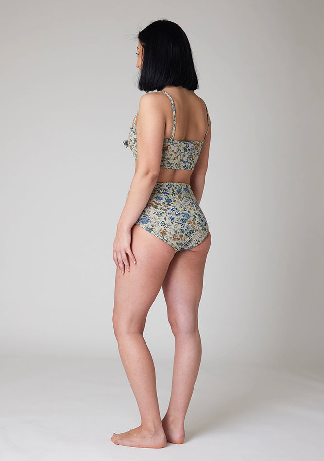 Back quarter image of a five-foot-six, size 8 model wearing Ugly Pants' Cream Floral Print Overnight period pants in moderate to heavy absorbency, paired with a cream floral print crop top, featuring a self tie detachable bow.