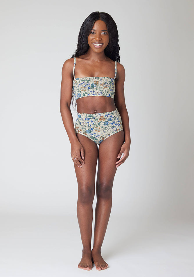 Front image of a five-foot, size 6 model wearing Ugly Pants' Cream Floral Print Overnight period pants in moderate to heavy absorbency, paired with a cream floral print crop top, featuring a self tie detachable bow, this image does not feature the self tie bow, but a straight neckline.