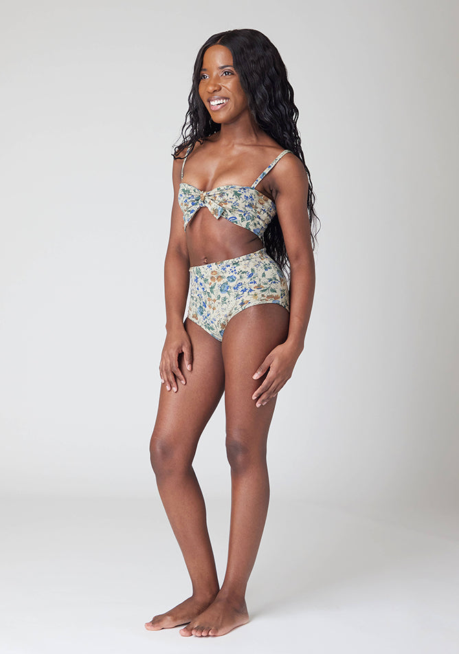 Front quarter image of a five-foot, size 6 model wearing Ugly Pants' Cream Floral Print Overnight period pants in moderate to heavy absorbency, paired with a cream floral print crop top, featuring a self tie detachable bow.