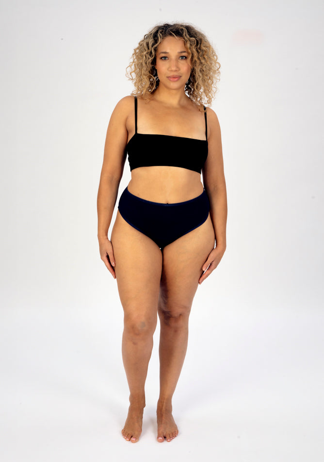 Front image of a five foot seven, size 16 model wearing Ugly Pants' navy high waisted period pants in light to moderate absorbency, paired with a black crop top.