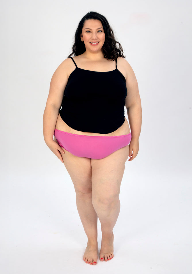 Front image of a five foot seven, size 22 model wearing Ugly Pants' pink high waisted period pants in super heavy absorbency, paired with a black cami top.