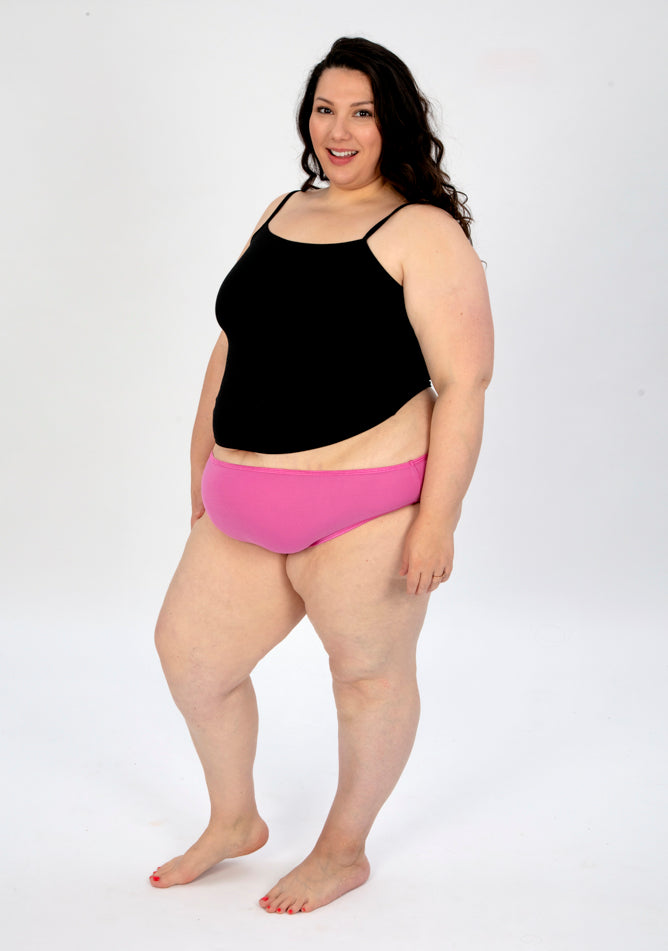 Front quarter image of a five foot seven, size 22 model wearing Ugly Pants' pink high waisted period pants in super heavy absorbency, paired with a black cami top.