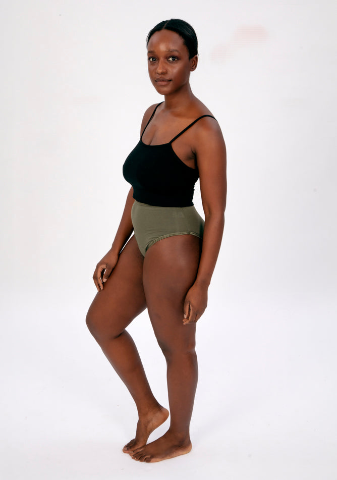 Front quarter image of a five foot four, size 10 model wearing Ugly Pants' olive high waisted period pants in light to moderate absorbency, paired with a black crop top.