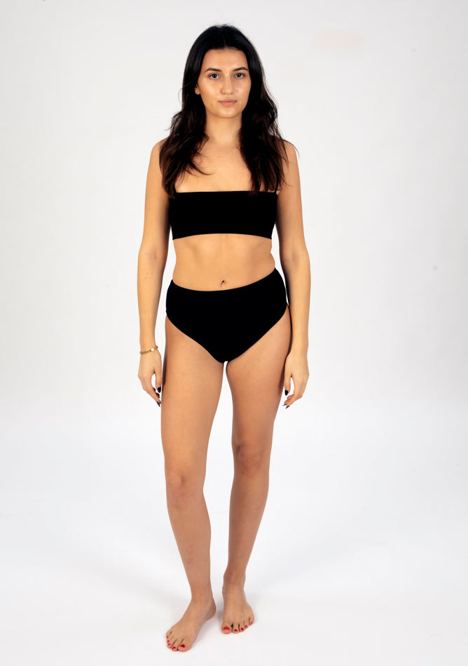 Front image of a five foot six, size 8 model wearing Ugly Pants' black high waisted period pants in light to moderate absorbency, paired with a black crop top.