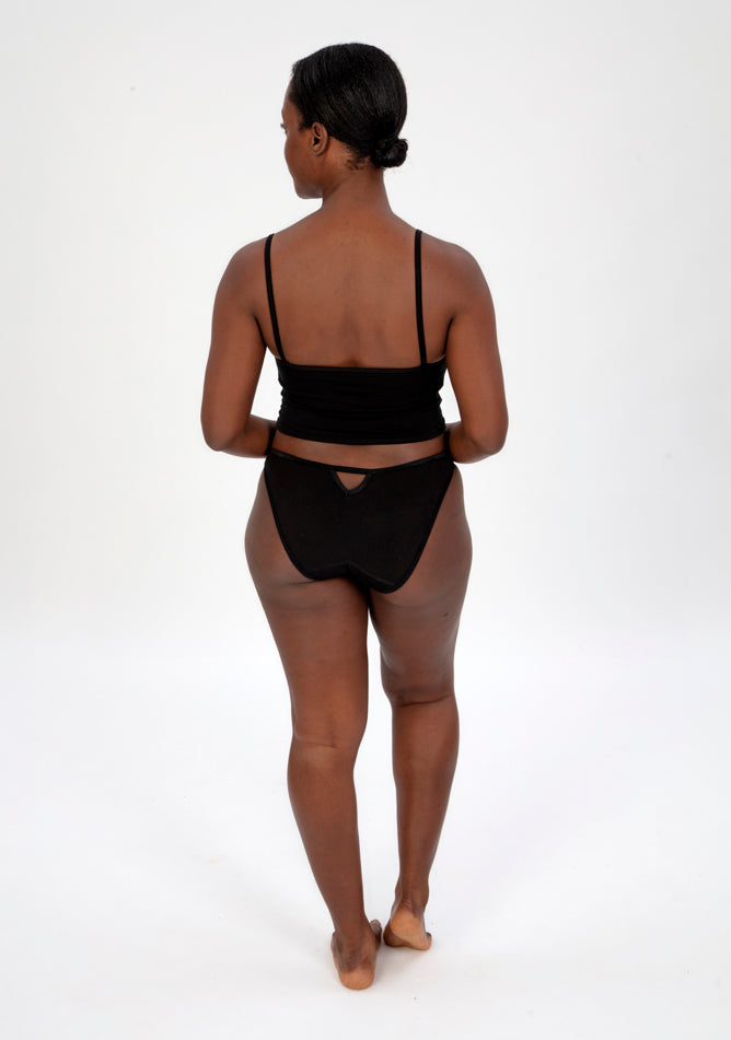 Back image of a five foot four, size 10 model wearing Ugly Pants' Black Lace Bikini Brief Period Pant in a light to moderate absorbency, paired with a black crop top.