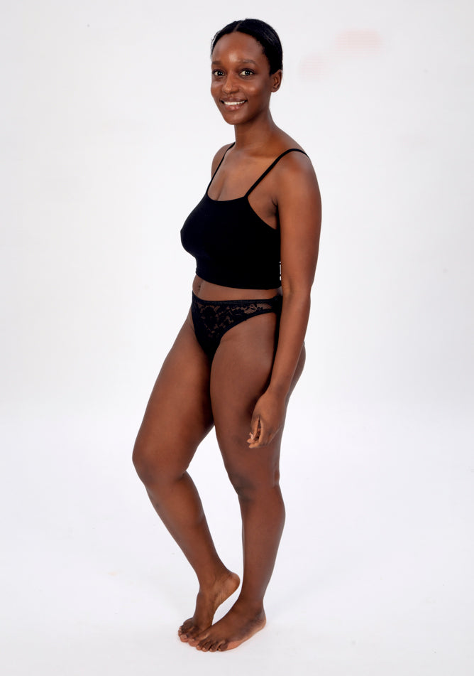 Front quarter image of a five foot four, size 10 model wearing Ugly Pants' Black Lace Bikini Brief Period Pant in a light to moderate absorbency, paired with a black crop top.