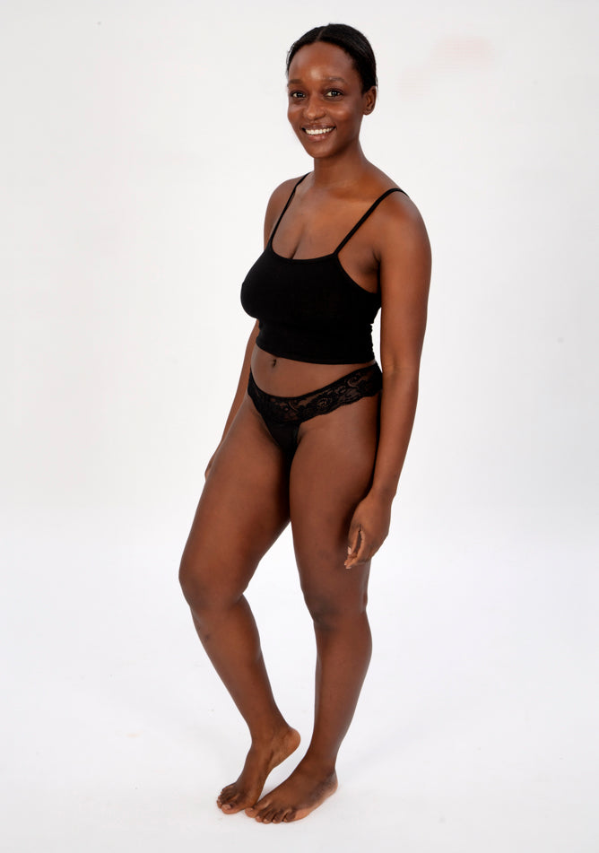 Front quarter image of a five foot four, size 1o model wearing Ugly Pants' Black Lace Thong period pants in a light absorbency, paired with a black crop top.