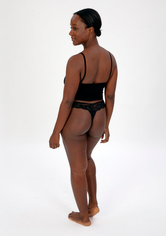 Back quarter image of a five foot four, size 1o model wearing Ugly Pants' Black Lace Thong period pants in a light absorbency, paired with a black crop top.