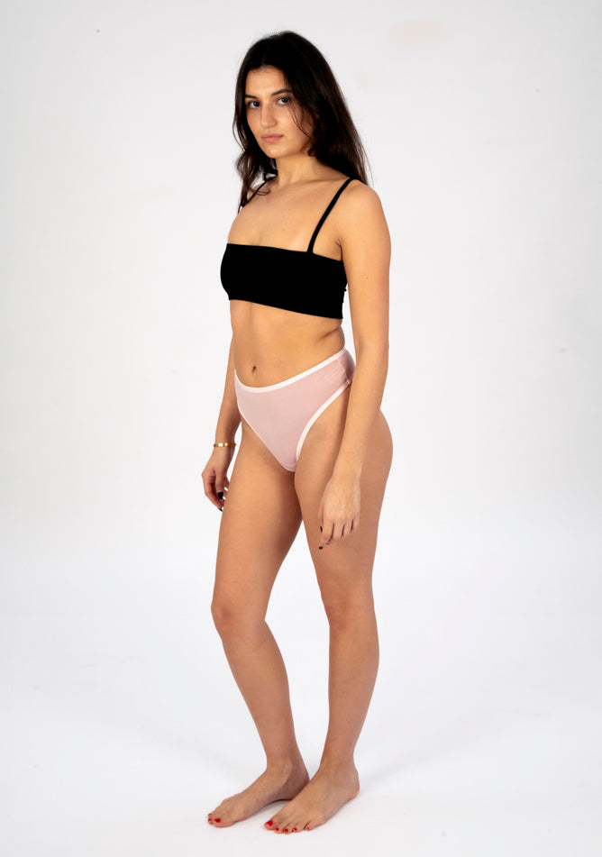 Front quarter image of a five foot six, size 8 model wearing Ugly Pants' blush high waisted period thong in light absorbency, paired with a black crop top.