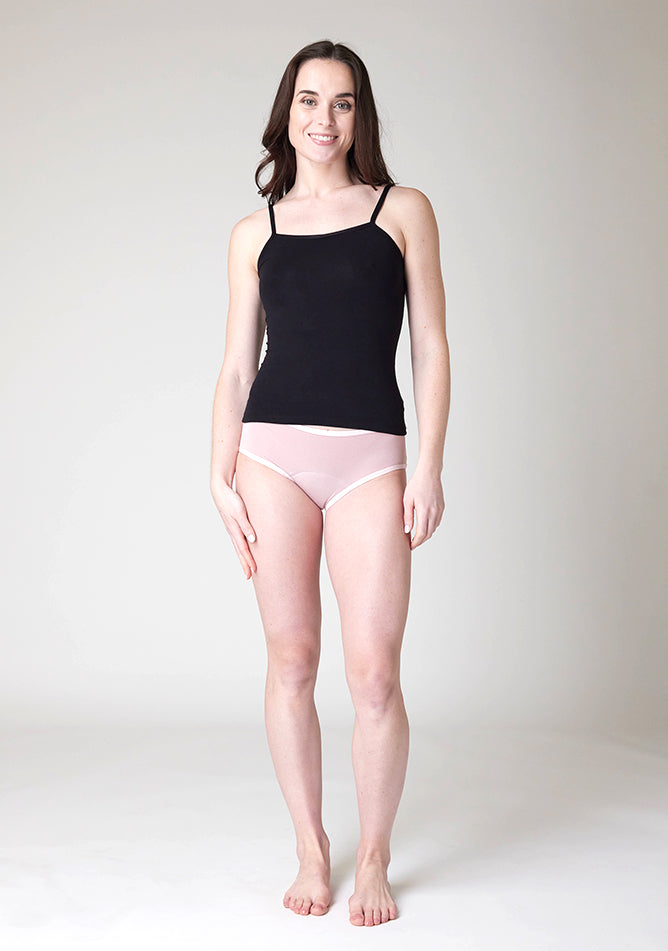 Front image of a five-foot-nine, size 8 model wearing Ugly Pants' Blush Hipster Brief Period Pants in moderate to heavy absorbency, paired with a black cami top