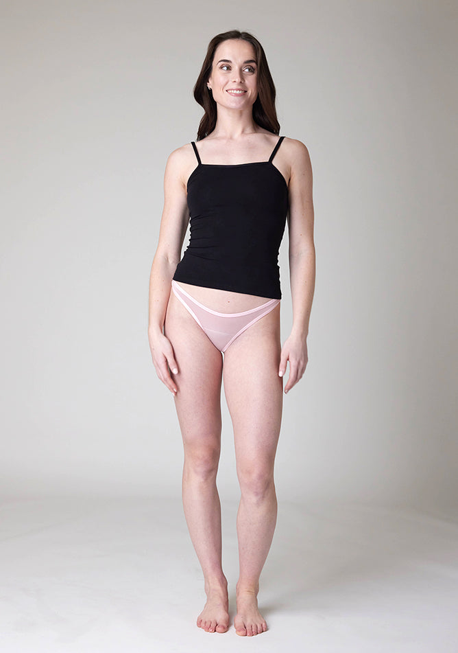 Front image of a five-foot-nine, size 8 model wearing Ugly Pants' Blush Thong period pants in a light absorbency, paired with a black cami top.