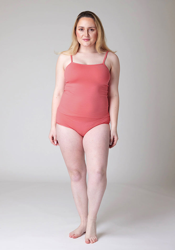 Front image of a five-foot-three, size 12 model wearing Ugly Pants' Coral Overnight flow sleep set with matching coral cami