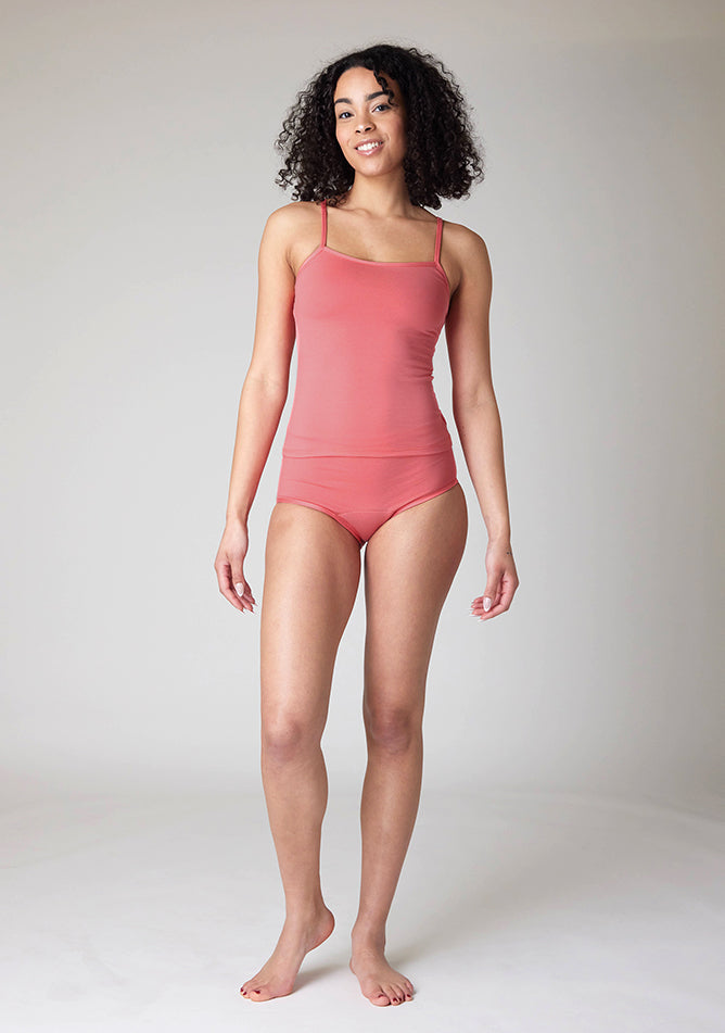 Front image of a five-foot-ten, size 10 model wearing Ugly Pants' Coral Overnight flow sleep set with matching coral cami