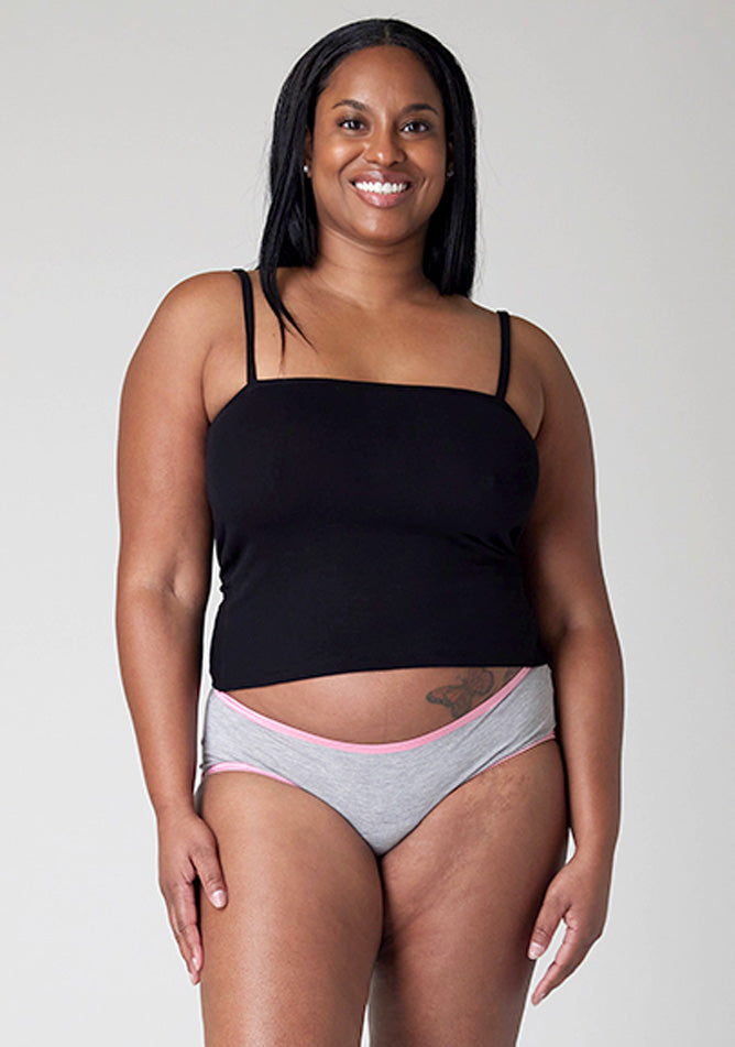Close up of a five-foot-five, size 10 model wearing Ugly Pants' Grey Hipster Brief Period Pants with light pink elastic in moderate to heavy absorbency, paired with a black cami top