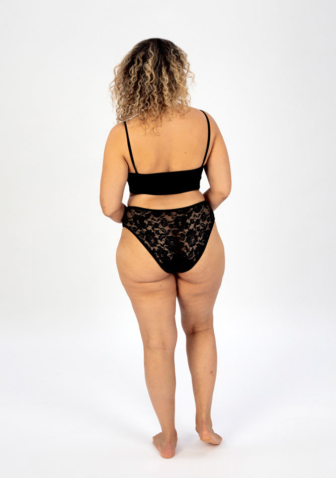 Back image of a five foot sveen, size 16 model wearing Ugly Pants' Black Lace High Waisted Period Pant in a light to moderate absorbency, paired with a black crop top.