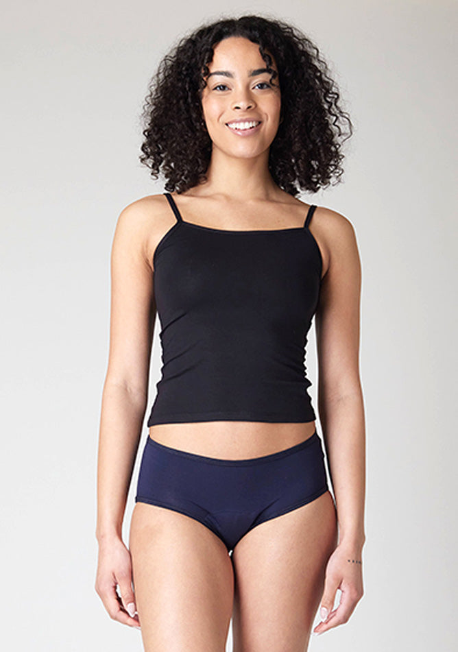 Close up image of a five-foot-ten, size 10 model wearing Ugly Pants' Navy Hipster Brief Period Pants in moderate to heavy absorbency, paired with a black cami top