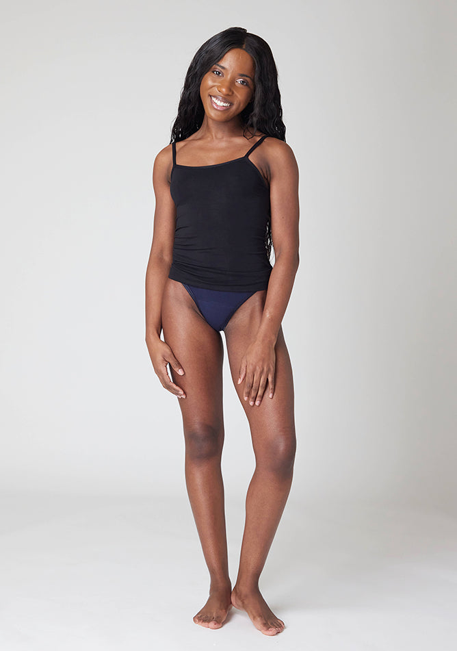 Front image of a five-foot, size 6 model wearing Ugly Pants' Navy Thong period pants in a light absorbency, paired with a black cami top.