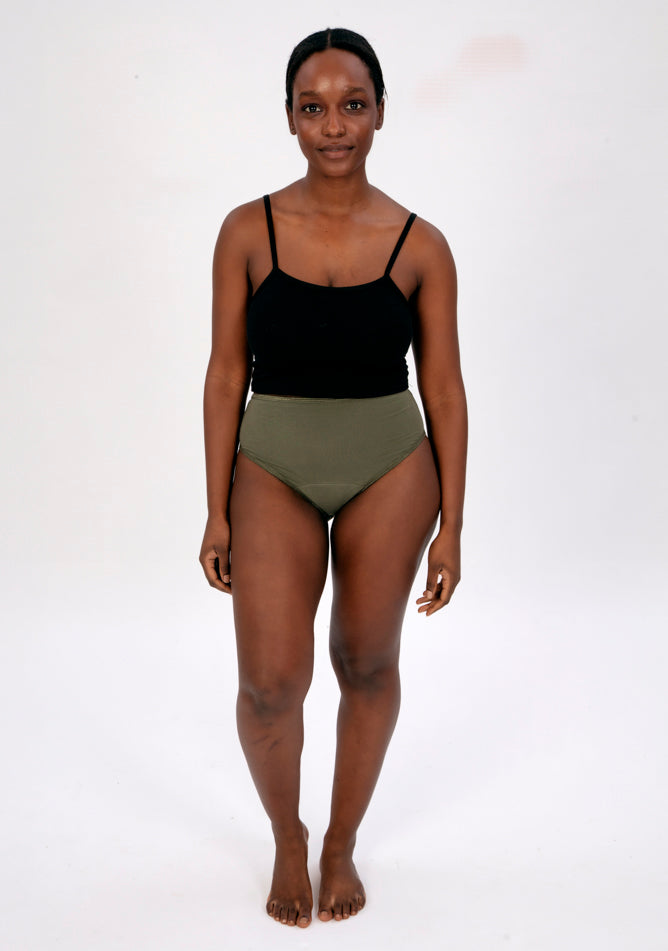 Front image of a five foot four, size 10 model wearing Ugly Pants' olive high waisted period pants in light to moderate absorbency, paired with a black crop top.