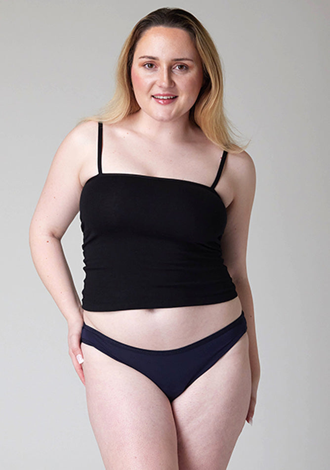 Close-up of a five-foot-five, size 12 model wearing Ugly Pants' Navy Bikini Brief period pants in light to moderate absorbency, paired with a black cami top. 