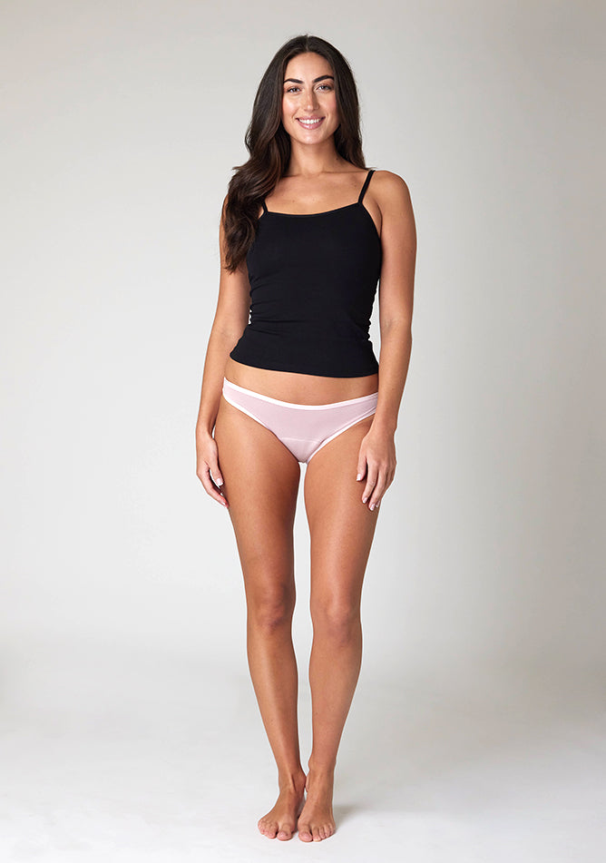 Front image of a five foot ten , size 10model wearing Ugly Pants' Blush Bikini Brief period pants in light to moderate absorbency, paired with a black cami top. 