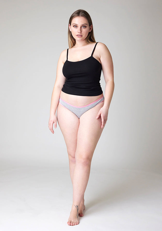 Front image of a five foot five, size 14 model wearing Ugly Pants' Grey Bikini Brief period pants with light pink elastic in light to moderate absorbency, paired with a black cami top