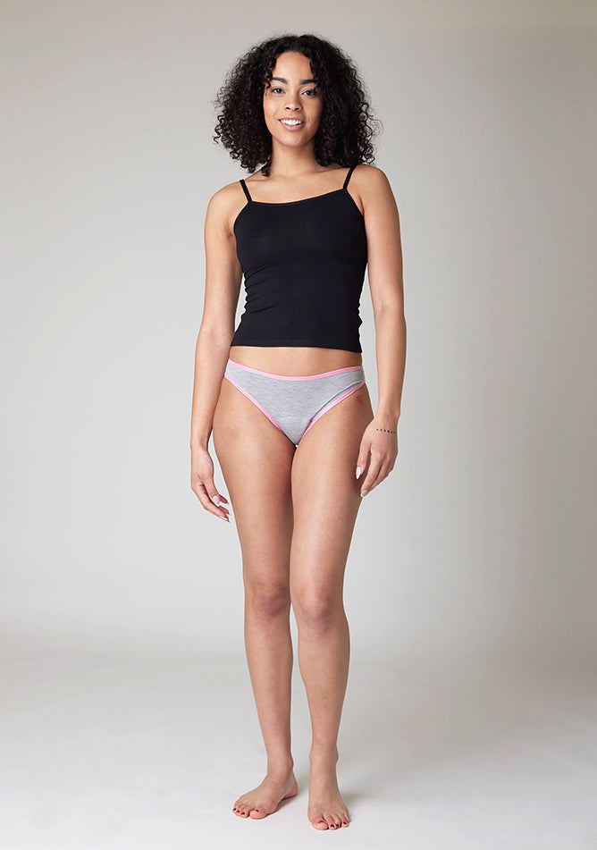 Front image of a five foot ten, size 10 model wearing Ugly Pants' Grey Bikini Brief period pants with light pink elastic in light to moderate absorbency, paired with a black cami top