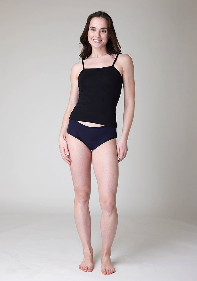 Front image of a five foot nine, size 8 model wearing Ugly Pants' Navy Hipster Brief Period Pants in light to moderate  absorbency, paired with a black cami top