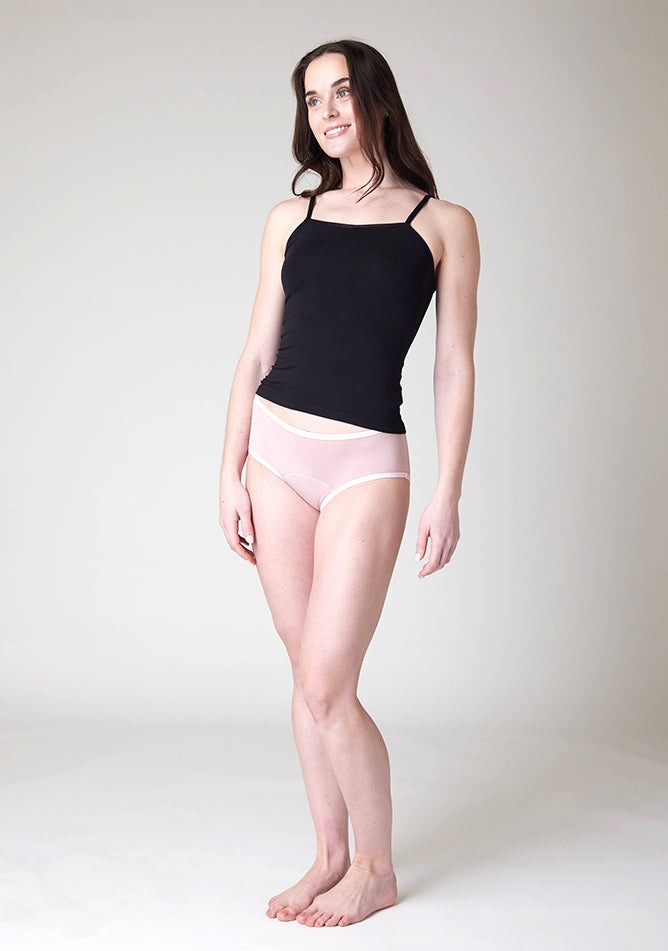 Quarter front image of a five foot nine, size 8 model wearing Ugly Pants' Blush Hipster Brief Period Pants in moderate to heavy absorbency, paired with a black cami top