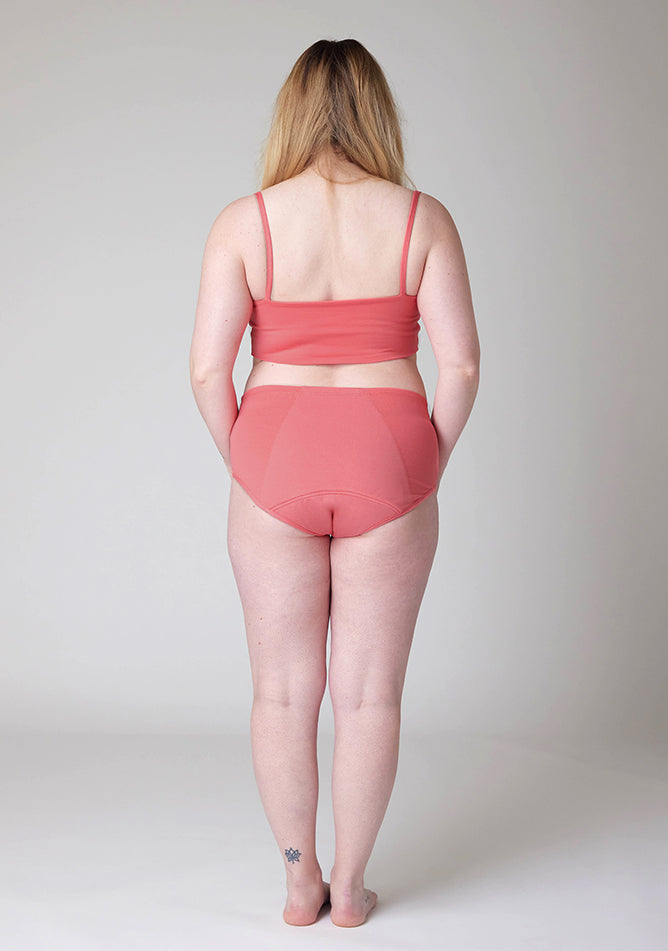 Back image of a five foot ten, size 12 model wearing Ugly Pants' Coral Overnight flow sleep set with matching coral crop top, featuring a self tie detachable bow.