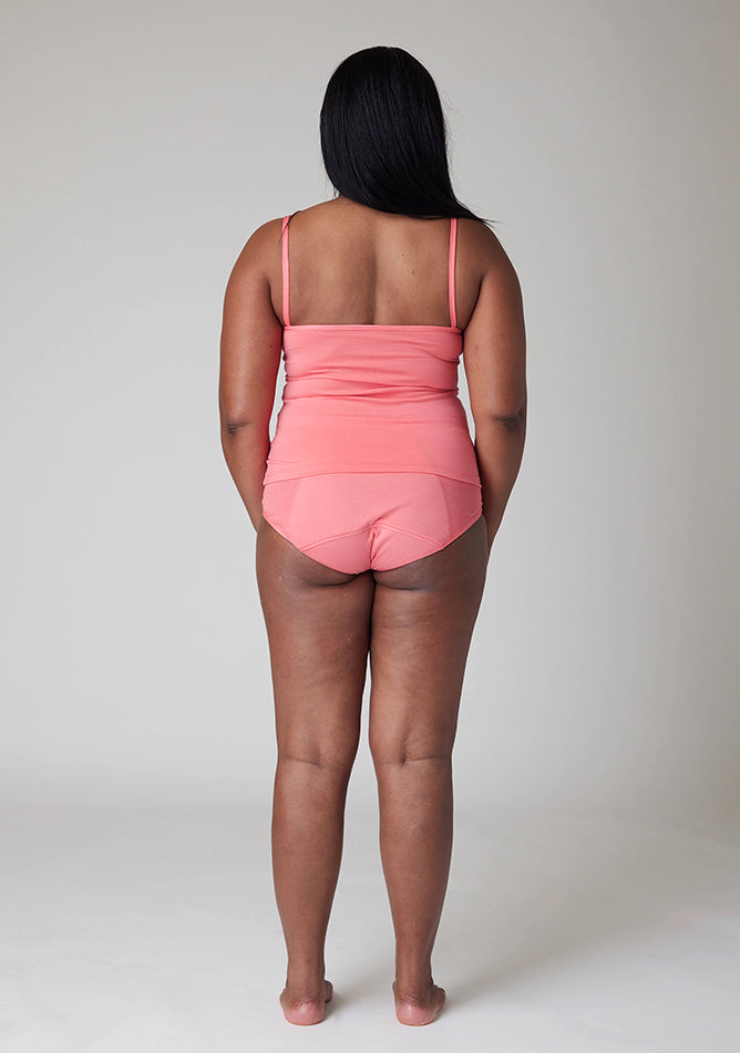 Back image of a five foot five, size 10 model wearing Ugly Pants' Coral Overnight flow sleep set with matching coral cami