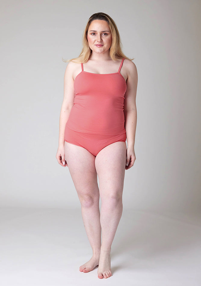 Front image of a five foot three, size 12 model wearing Ugly Pants' Coral Overnight flow sleep set with matching coral cami