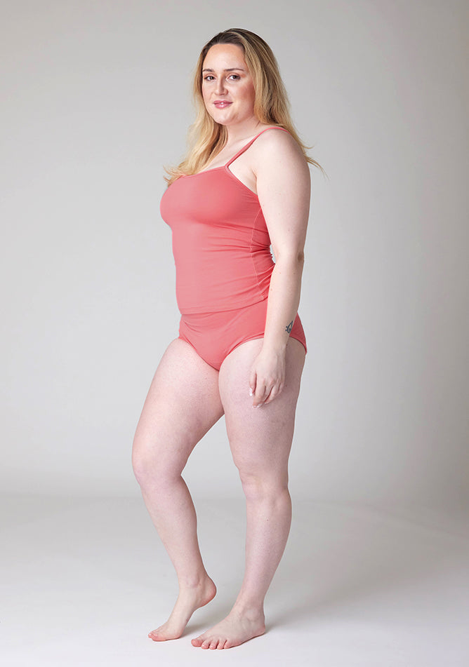 Quarter front image of a five foot three, size 12 model wearing Ugly Pants' Coral Overnight flow sleep set with matching coral cami
