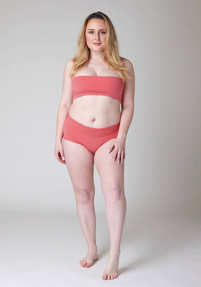 Front image of a five foot three size 12 model wearing Ugly Pants' Coral Overnight flow sleep set with matching coral crop top, this image does not feature the self tie bow, but a straight neckline. 
