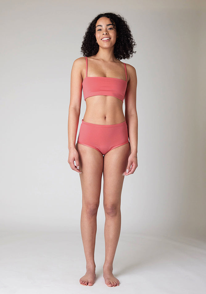 Front image of a five foot ten size 10 model wearing Ugly Pants' Coral Overnight flow sleep set with matching coral crop top, this image does not feature the self tie bow, but a straight neckline. 