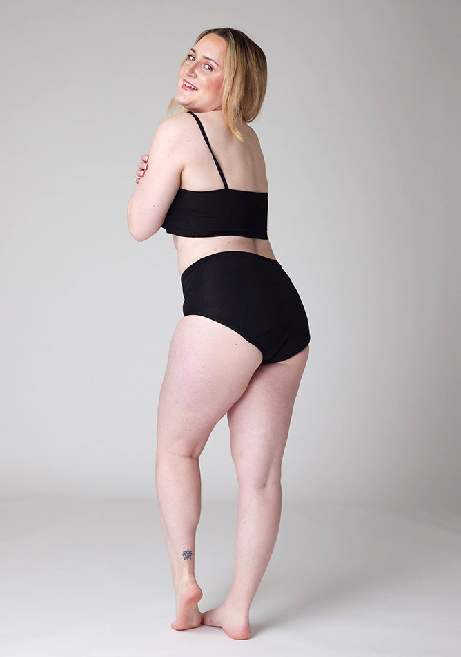 Quarter back image of a model wearing Ugly Pants' Black Overnight flow sleep set with matching black crop top.
