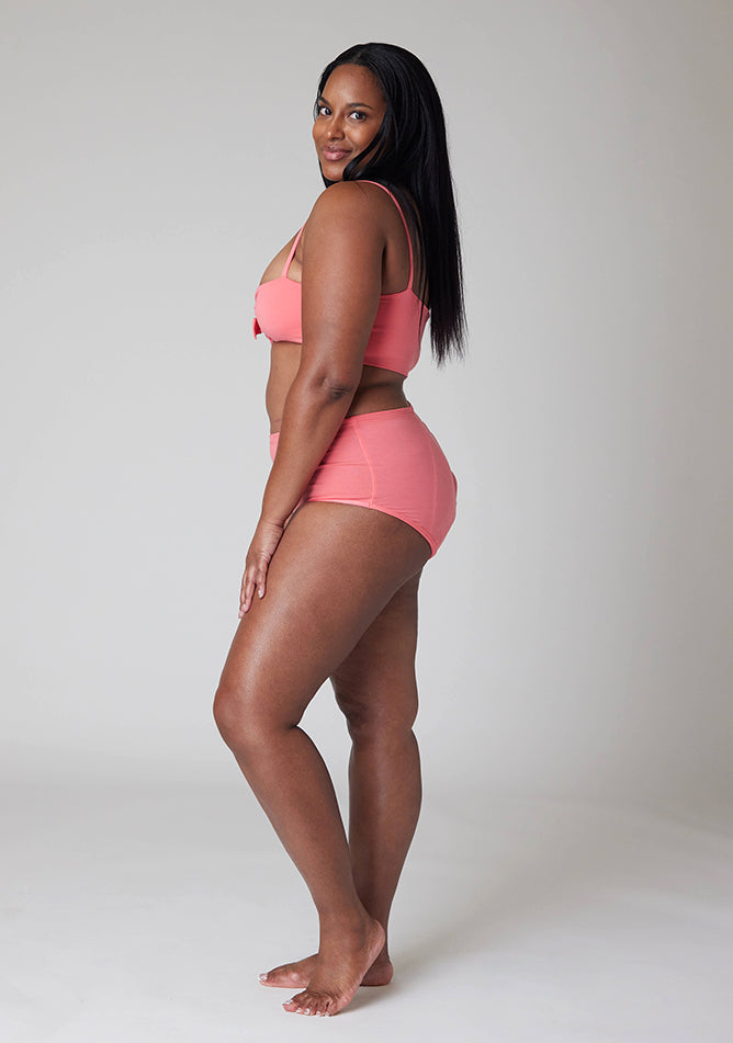 Quarter back image of a five foot ten, size 10 model wearing Ugly Pants' Coral Overnight flow sleep set with matching coral crop top, featuring a self tie detachable bow.