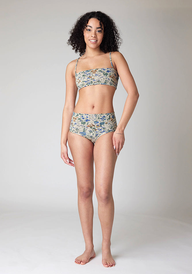 Back image of a five foot ten, size 10 model wearing Ugly Pants' Cream Floral Print Overnight flow sleep set with matching cream floral print crop top with a self tie detachable bow,  but a straight neckline.