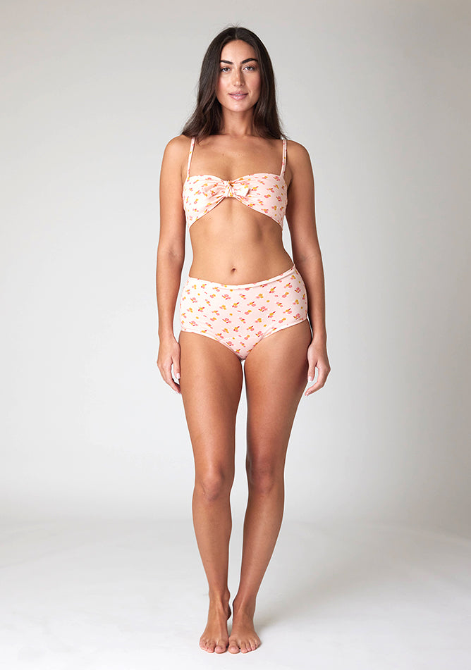 Front image of a five foot ten, size 10 model wearing Ugly Pants' Pink Floral Print Overnight period pants in moderate to heavy absorbency, paired with a pink floral print crop top, with a self tie detachable bow.