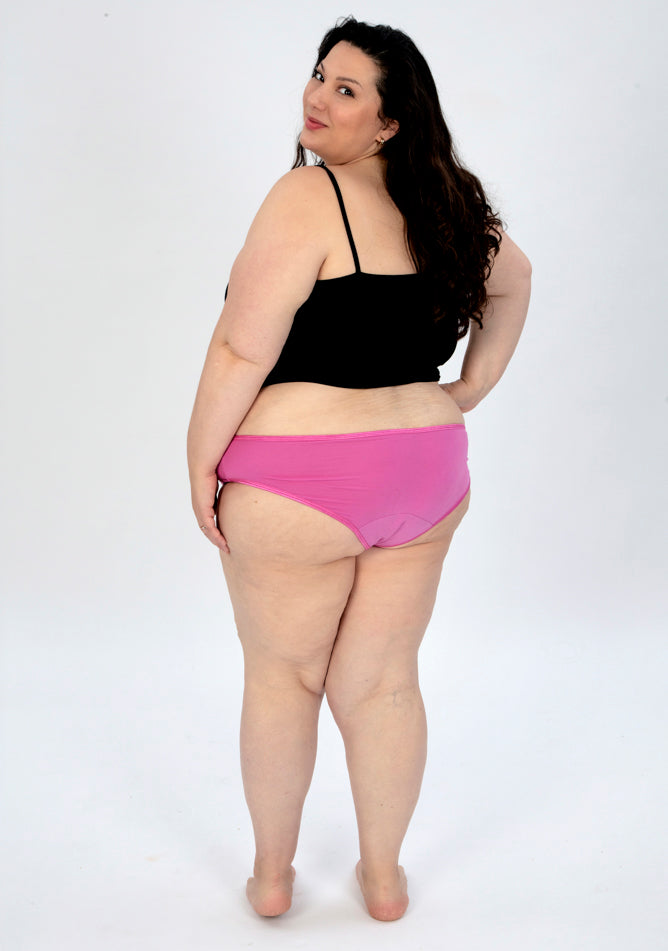 Back image of a five foot seven, size 22 model wearing Ugly Pants' pink high waisted period pants in super heavy absorbency, paired with a black cami top.
