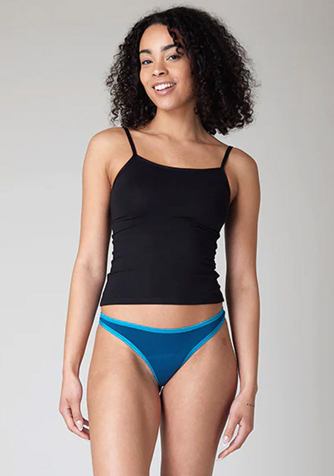 Close-up image of a five-foot-ten, size 10 model wearing Ugly Pants' Teal Thong period pants in a light absorbency, paired with a black cami top.