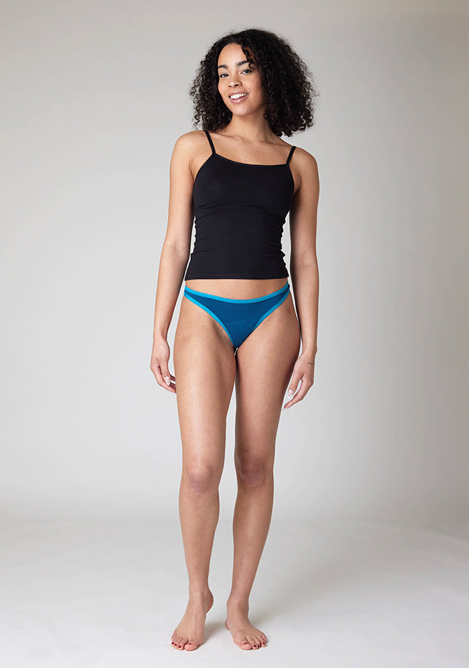 Front image of a five-foot-ten, size 10 model wearing Ugly Pants' Teal Thong period pants in a light absorbency, paired with a black cami top.